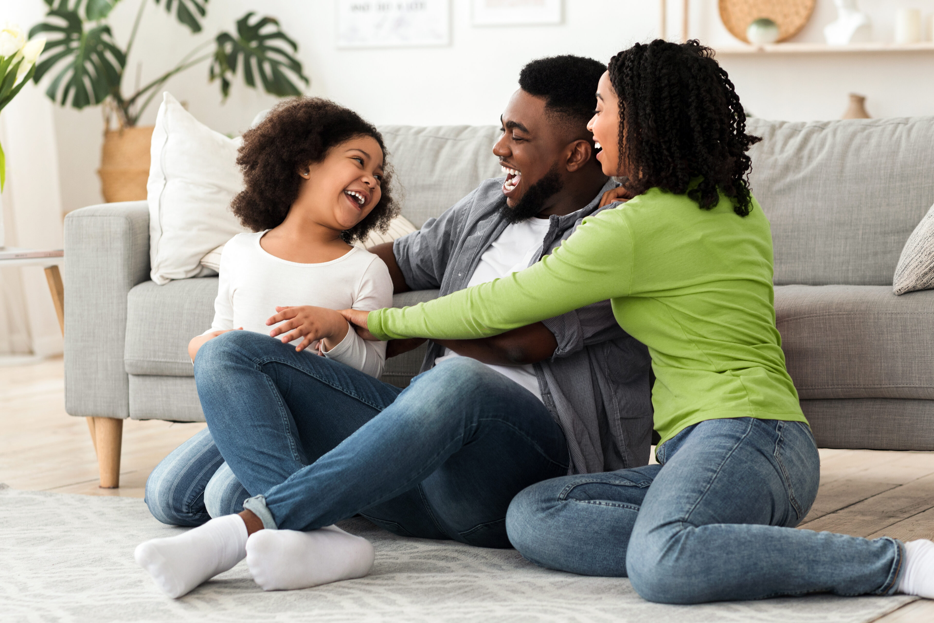 Cheerful black family having fun at home, parents tickling their daughter Cheerful black family having fun at home, parents tickling their daughter, laughing together, spending quarantine time in isolation, free space