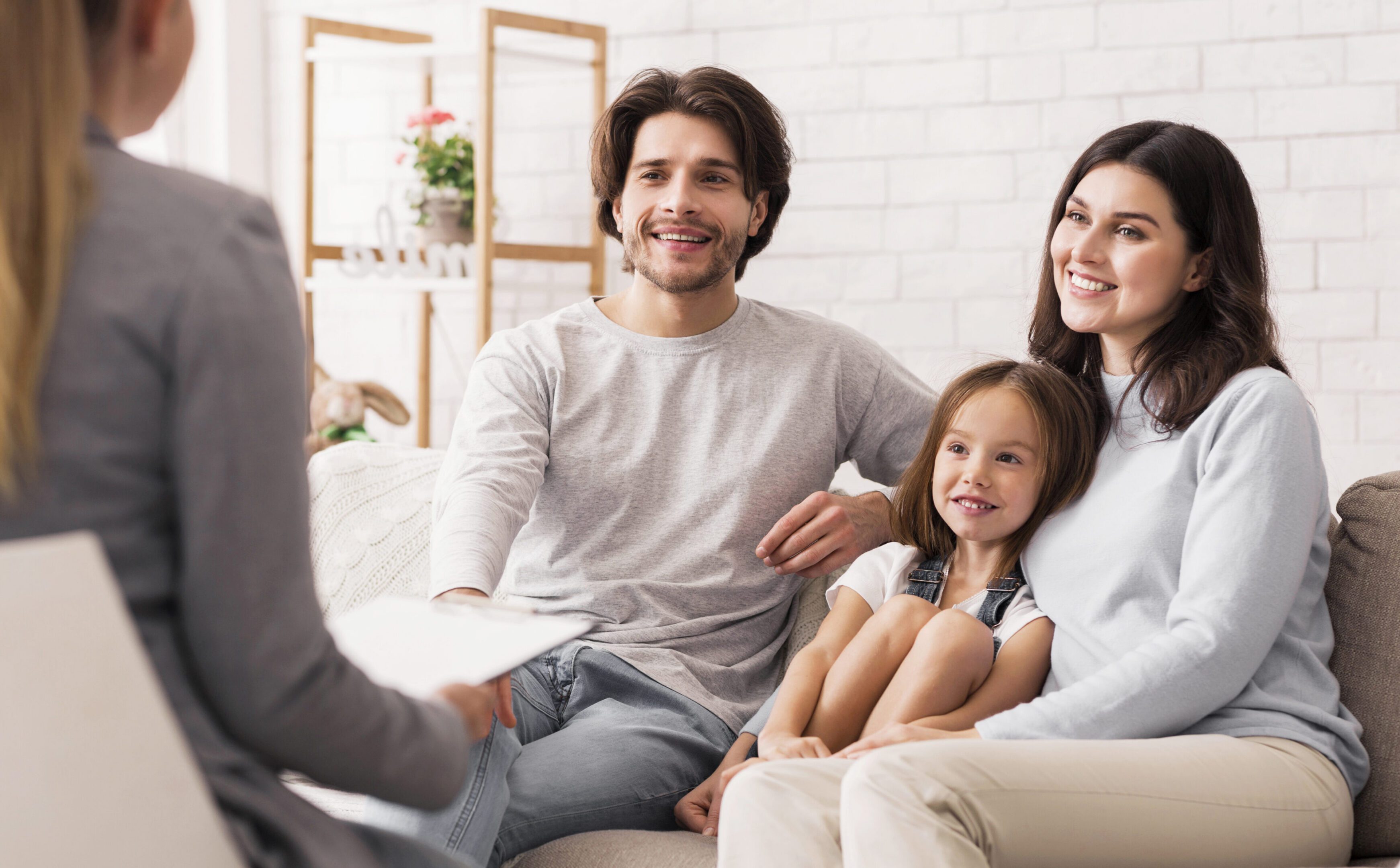 Happy Parents With Little Daughter Sitting Together At Psycholigist's Office After Successful Family Therapy